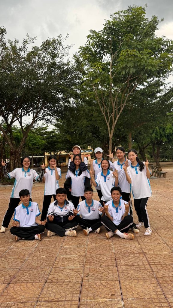 Cả tổ đứng giữa sân cây, cười và tạo dáng cùng nhau.